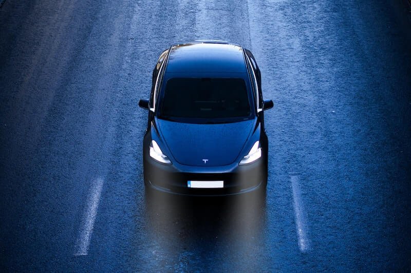 An electric vehicle Tesla driving down the road