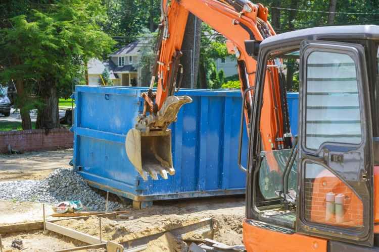 A digger loading a 20 yard dumpster with dirt