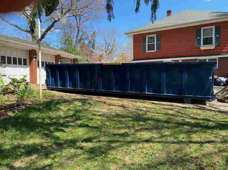 Dumpster in driveway of orange house 