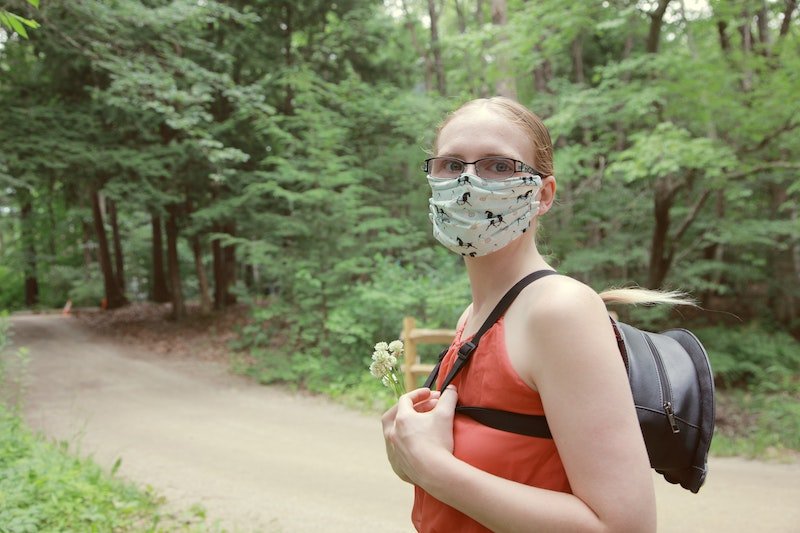 A female hiker in the woods with a mask on