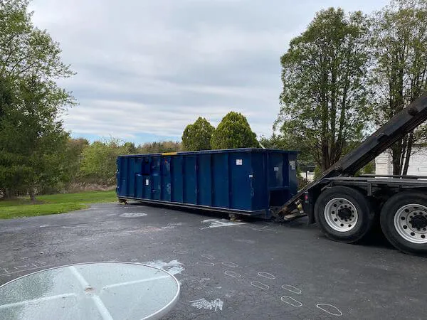 Image of blue roll off bin near trees