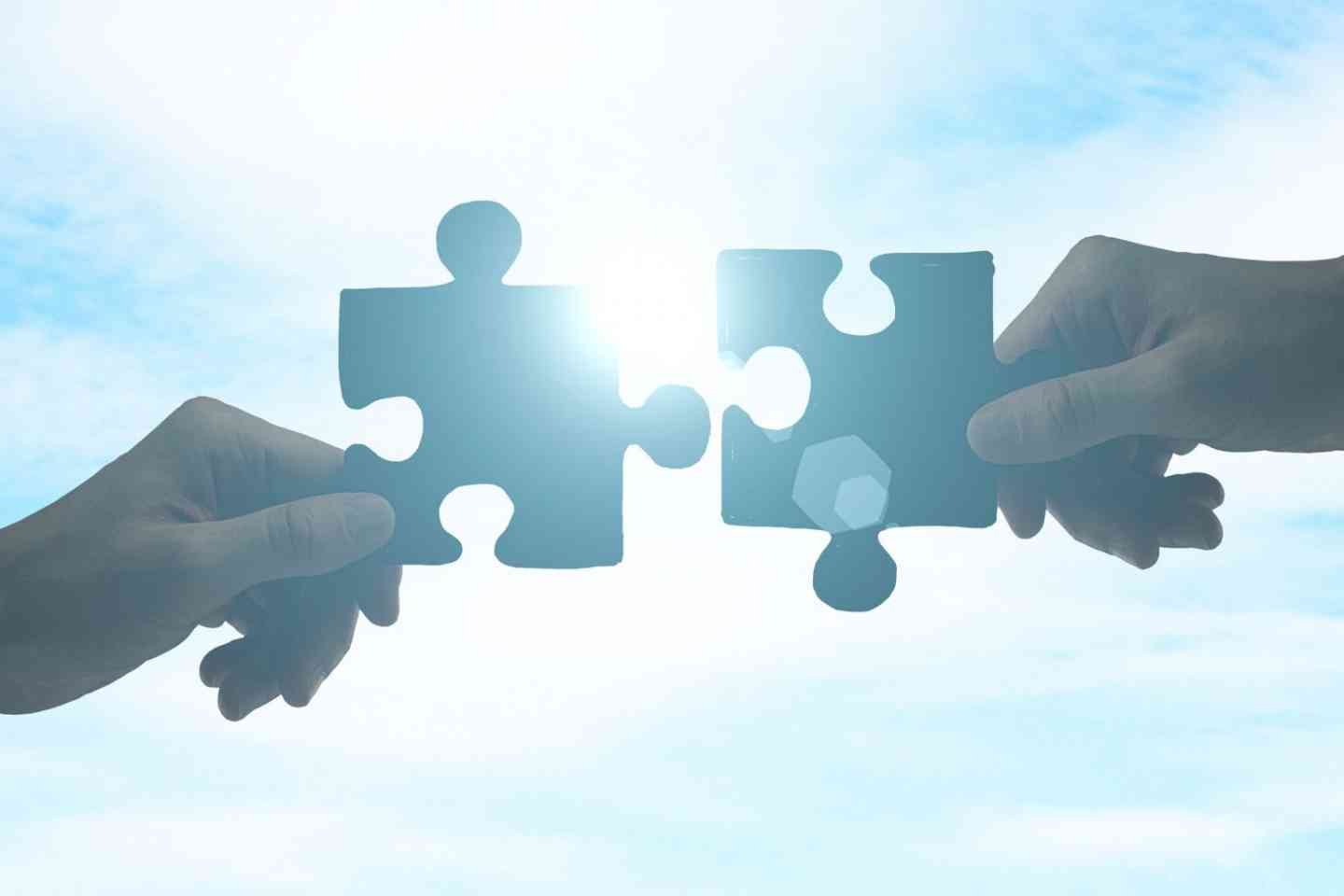 Two hands bringing puzzle pieces together