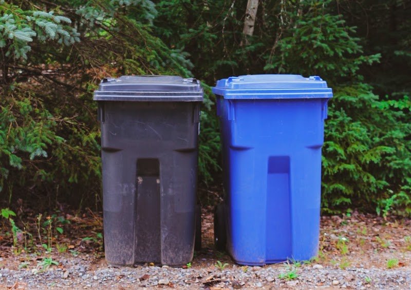A black trash can next to a blue recycling can