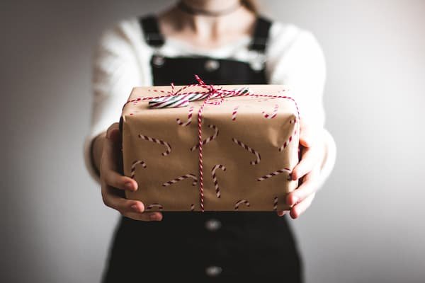 someone giving out a gift wrapped in brown paper
