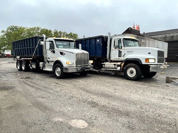 two roll off trucks side by side