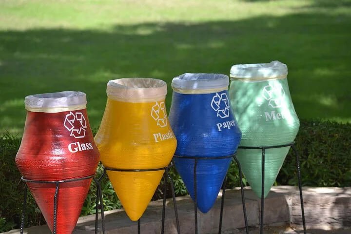 Different colored recycling bins for glass, plastic, paper, and metal